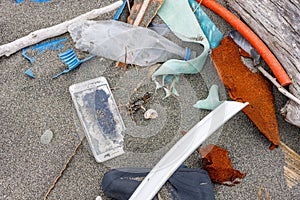 A lot of rubbish from plastic and a smartphone on the sand on the seashore