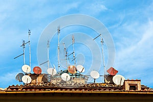 A lot of satellite dish antennas on the house against blue sky background in Italy