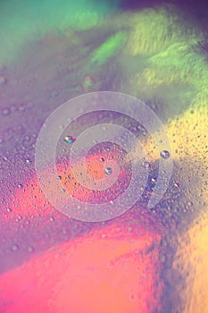 A lot of small drops of water on a colorful pastel holographic background. Abstract background with copy space