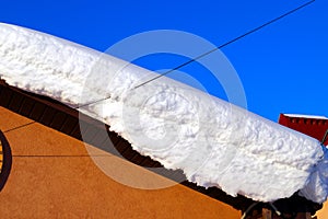 A lot of snow lies on a residential building and large snowdrifts around