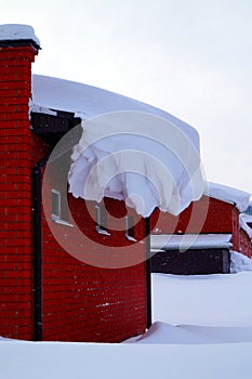 A lot of snow lies on a residential building and large snowdrifts around