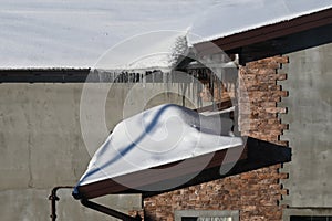 A lot of snow on the roofe. Winter icicles hanging from eaves of roof.