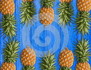 A lot of succulent pineapples on the blue wooden table. Healthy dietary food