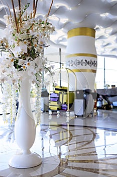 a lot of suitcases are on a trolley in a beautiful bright lobby of the hotel with flowers in a vase
