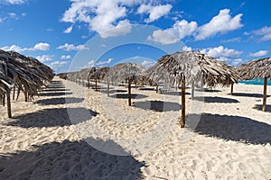 a lot of thatched sun shelters. Straw umbrella on empty seaside beach in Varadero, Cuba. Relaxation, vacation idyllic background