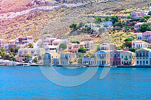 A lot of tiny colorful houses on the rocky shore of Mediterrenean sea on Simy greek island