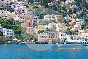 A lot of tiny colorful houses on the rocky shore of Mediterrenean sea on Simy greek island