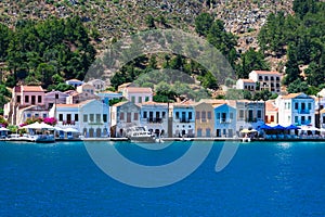 A lot of tiny colorful houses on the rocky shore of Mediterrenean sea on Simy greek island in sunny summer day,