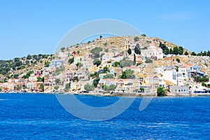 A lot of tiny colorful houses on the rocky shore of Mediterrenean sea on Simy greek island in sunny summer day, tourism