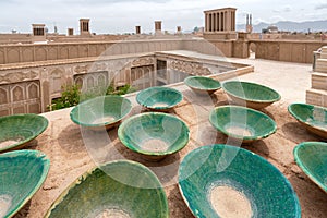 Lot of traditional green bowls on the roof of persian city. Clay bowls with rooftops of Yazd, Iran, in the background
