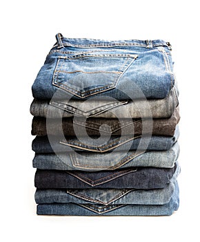 Lot of used jeans stacked in a pile isolated on white