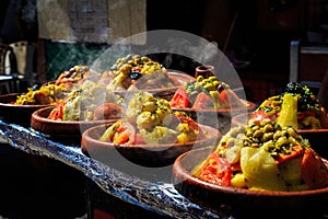 A lot of warm tagines with delicious vegetables on a market