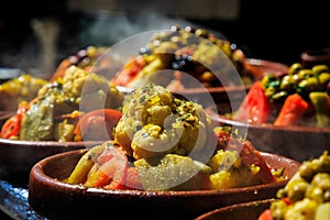 A lot of warm tagines with delicious vegetables on a market