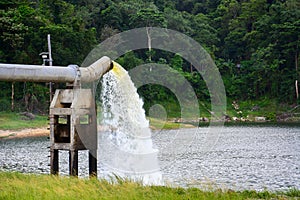 Lot of water gushing out of the big metal pipe to the lake, pump water fill in reservoir