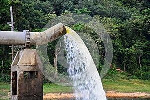 Lot of water gushing out of the big metal pipe to the lake, pump water fill in reservoir