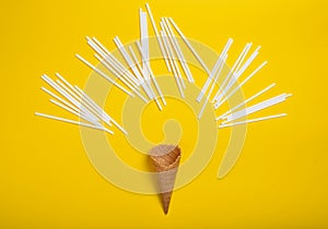 A lot of white cocktail tubes and a waffle horn on a yellow background. Creative layout, top view, minimalist trend, flat lay.
