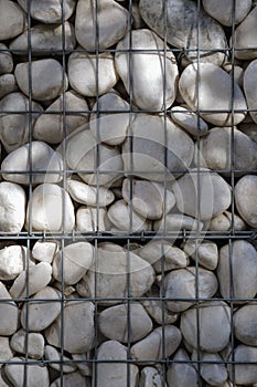 A lot of white polished pebbles behind a metal grid