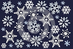 A lot of white snowflake painted with paint through a stencil on a dark blue background.