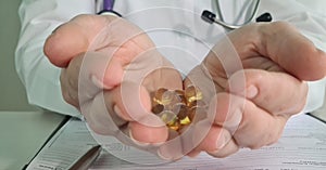 Lot of yellow capsules of omega-3 vitamin D and E lies on doctor hand