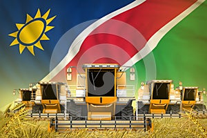 a lot of yellow farming combine harvesters on grain field with Namibia flag background - front view, stop starving concept -