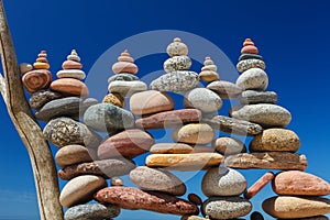 Lots of balanced multicolored stones on the beach against the blue sky