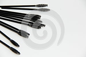 Lots of black mascara brushes on aa lot of black mascara brushes are lying on a white background close up