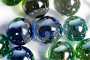 Lots of blue and green glass balls, beads on a white background, close-up