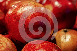 Lots of bright juicy pomegranates on the counter. Seasonal fruit. Healthy eating and vegetarianism. Close-up