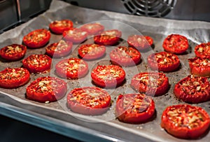 Lots of chopped sun-dried tomatoes with spices, garlic and olive oil in the oven. Close-up