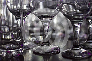 Lots of clean empty glasses of drinks on the bar in a nightclub. Glare and reflections on the glasses in the dark