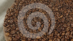 Lots of coffee beans on wooden board with dissipating steam. Roasted beans for preparation of fragrant drink.