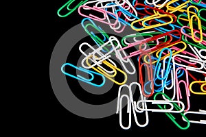 Lots of colored paper clips isolated on black background