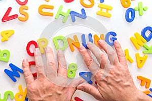 Lots of colorful letters on a table, hands forming german word, keep order
