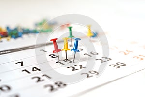 Lots of colorful pins on the calendar close-up with selective focus. The concept of planning.