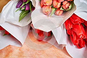 Lots of delicate bouquets of red and lilac tulips, top view. A selected bouquet of beautiful red tulips in a package.The