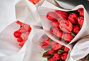 Lots of delicate bouquets of red tulips, top view. A selective focus of beautiful red tulips in a package.The concept of