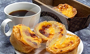 Lots of desserts Pastel de nata or Portuguese egg tart with a white cup of black coffee. Pastel de Belm is a small pie