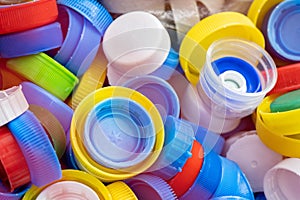Lots of different colored plastic drink bottle caps in a designated recycling container, throwing away and collecting bottle caps