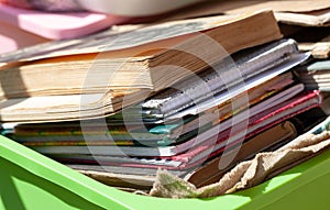 Lots of different old books and paper notebooks in a container outside in sunlight, stack. Box full of old literature, giving away