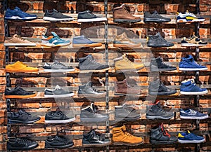 Lots of different shoes sneakers, boots, plimsolls on the showcase in market. Image of sport tracking boots on a shop-window in th