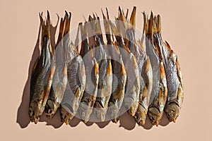 Lots of dried or jerky salty roach, palatable clipfish on pink background. Famous beer snack. Traditional way of