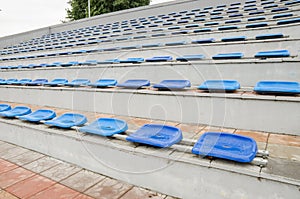 Lots of empty seats in the stadium. Texture of blue chairs. Plastic seats are arranged in a row. Dirty and scratched fan seats. St