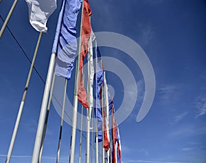 Lots of flags flying in the wind against the blue sky