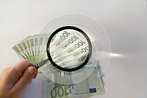 Lots of hundred Euro bills and magnifying glass