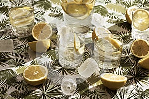 lots of lemons on top of a flower table and a pitcher of lemonade with glasses of water and ice. Cool drink in summer season. food