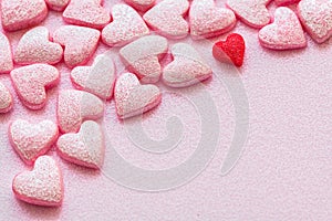 Lots of little pink sweet hearts and one red heart  on pink surfase