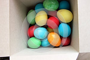 Lots of multi-colored Easter eggs in a white square box. Easter preparations