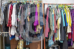 Lots of old, colorful clothes hung chaotically on the iron railings near the closets