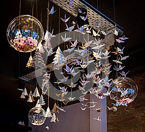 Lots of origami swans hanging from the roof, seen from underneath in a softly illuminated room