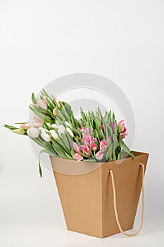 Lots of pink, white and salmon tulips in crafting packaging close-up on a white background.